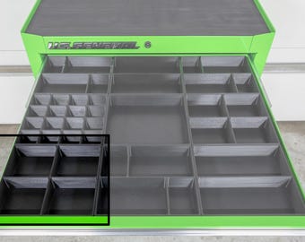 May include: A green and black tool chest with multiple open drawers. The drawers are divided into various compartments of different sizes. The top of the tool chest is black, and the brand name "U.S. GENERAL" is visible on the front.