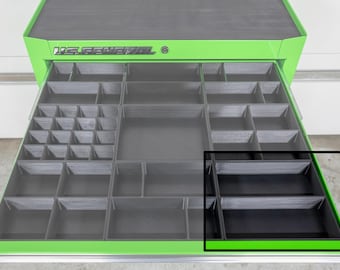 May include: A green and black US General tool chest with an open drawer. The drawer is divided into multiple compartments of varying sizes. The tool chest is on a light gray surface.