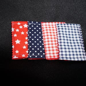 May include: Four fabric rectangles with patriotic patterns: red stars, navy blue polka dots, red and white gingham, and blue and white gingham. Each rectangle has a red zigzag edge.