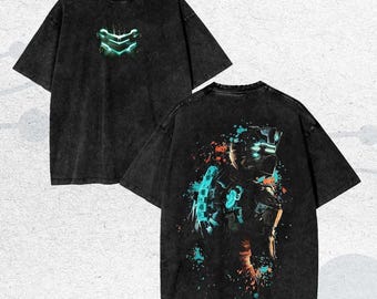 May include: Black graphic t-shirt featuring a neon green and blue design on the front and back. The front design is a stylized emblem, while the back showcases a character illustration with splatter effects. The shirt has a vintage wash.