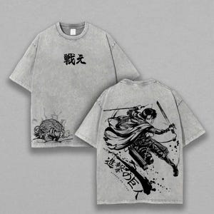 Könnte beinhalten: Graue T-Shirts mit Rundhalsausschnitt und kurzen Ärmeln. Die Vorderseite des Shirts hat japanischen Text und eine Grafik. Die Rückseite des Shirts zeigt eine Schwarz-Weiß-Illustration eines Charakters mit Schwertern und japanischem Text.