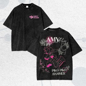 May include: Black oversized t-shirt with pink graphics. The front features "AMY TEAM" text and a logo. The back displays "AMY Rose" text, a character illustration with a hammer, and "PIKO PIKO HAMMER" text.