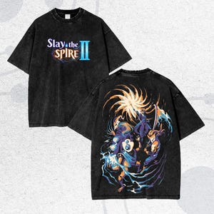 May include: Black t-shirt with the text "Slay the Spire II" on the front. The back of the shirt features a colorful graphic of characters in action. The shirt has a vintage, washed look.