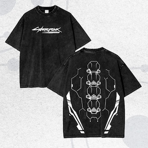 May include: Black t-shirt with the text "Cyberpunk" in white on the front. The back of the shirt features a white geometric design. The shirt has a vintage, washed look.