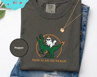 Comfort Colors Funny Cat Riding Dinosaur Shirt, This Is An Outrage Tee, Sarcastic Raptor Cat Rider Gift, Quirky Meme T-shirt for Cat Lover