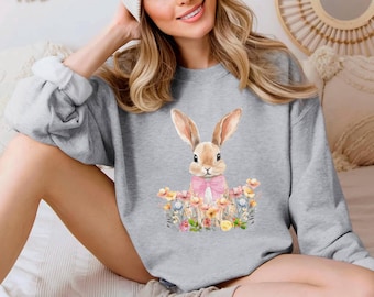 May include: A gray sweatshirt with a watercolor illustration of a brown bunny wearing a pink bow and surrounded by flowers.