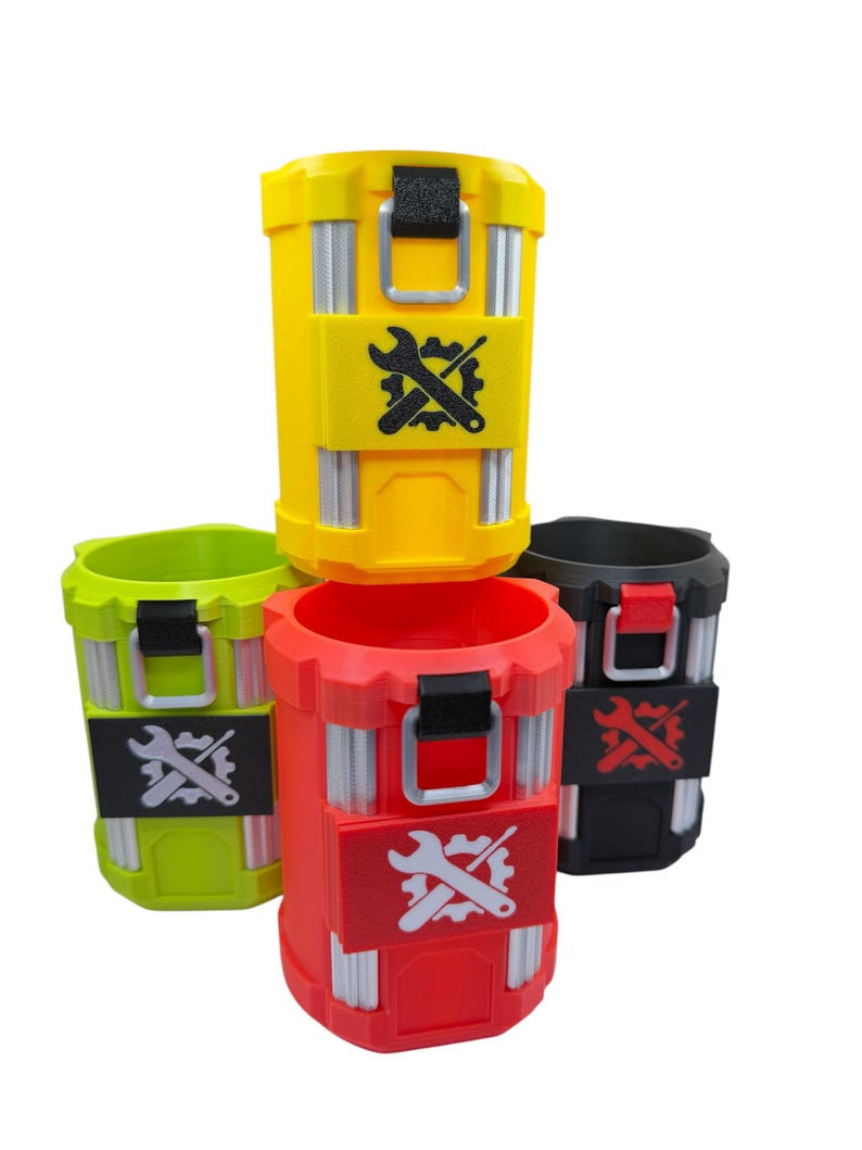May include: A collection of four cylindrical containers in yellow, lime green, red, and black. Each container features vertical silver-toned accents, a top latch, and a rectangular patch on the front displaying a graphic of a wrench crossed with a gear.