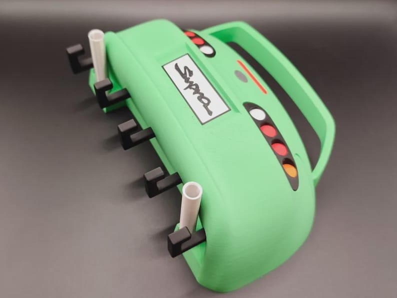 May include: A light green device with a handle, the word "Supra" on a white rectangle, and several black and white components. It has a series of colored lights and a handle. The device has a unique design.