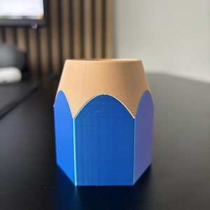 May include: A blue and brown pencil-shaped desk organizer. The organizer is made of plastic and has a hexagonal shape.