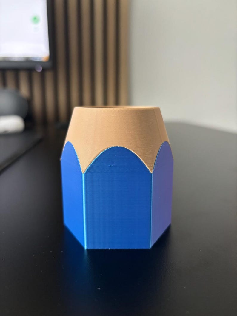May include: A blue and brown pencil-shaped desk organizer. The organizer is made of plastic and has a hexagonal shape.