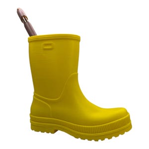 May include: A bright yellow rubber boot, possibly a pencil holder, with a brown and silver pen inside. The boot has a ridged sole and a smooth, glossy finish. The background is plain white.