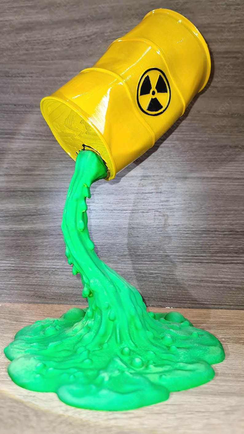 May include: A yellow barrel with a black radiation symbol is tilted, pouring out a stream of bright green liquid. The liquid pools on the surface, creating a unique decorative piece.
