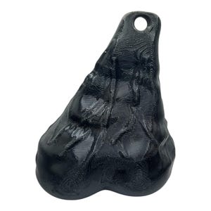 May include: A black, three-dimensional, organic-shaped pendant with a glossy finish and a visible layered texture. The object features a rounded, bulbous base that tapers upward to a narrow point, which contains a circular hole for hanging.