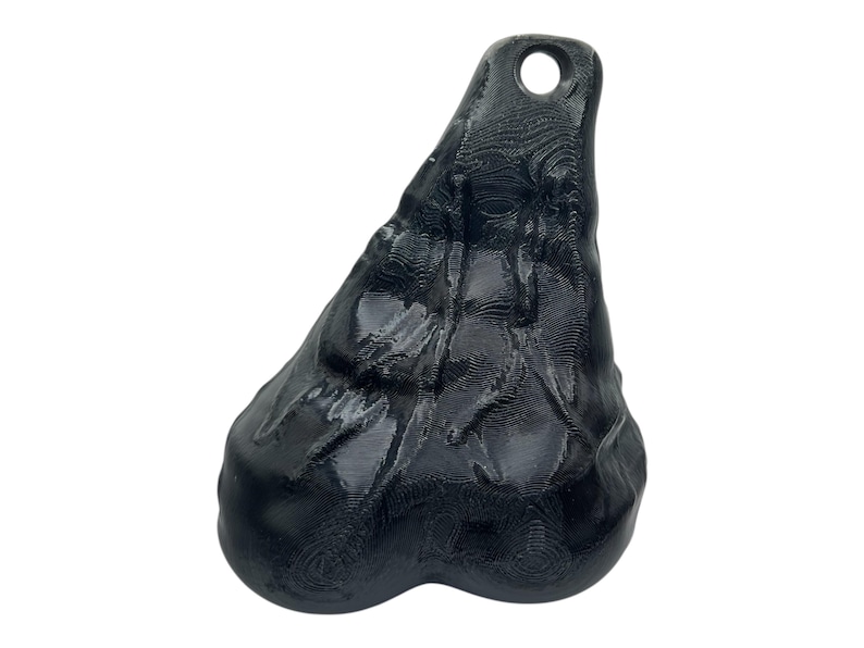 May include: A black, three-dimensional, organic-shaped pendant with a glossy finish and a visible layered texture. The object features a rounded, bulbous base that tapers upward to a narrow point, which contains a circular hole for hanging.
