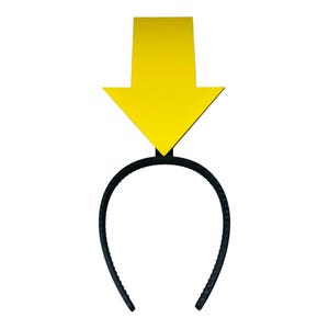 May include: A black plastic headband with a large, yellow arrow pointing downwards. The arrow is a solid color and is attached to the headband's center. The headband is a simple, curved design.