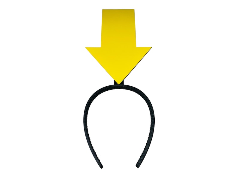 May include: A black plastic headband with a large, yellow arrow pointing downwards. The arrow is a solid color and is attached to the headband's center. The headband is a simple, curved design.