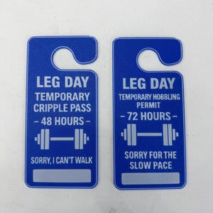 K&ouml;nnte beinhalten: Zwei blaue rechteckige T&uuml;ranh&auml;nger mit abgerundeten Oberteilen. Der linke lautet "LEG DAY TEMPORARY CRIPPLE PASS - 48 STUNDEN -" mit einer Hantelgrafik und "SORRY, I CAN'T WALK." Der rechte sagt "LEG DAY TEMPORARY HOBBLING PERMIT - 72 STUNDEN -" mit einer Hantelgrafik und "SORRY FOR THE SLOW PACE."