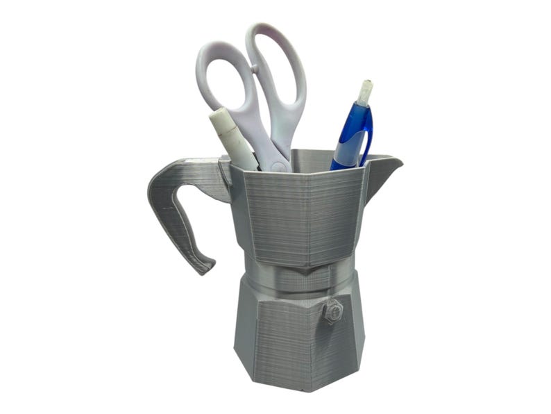 May include: A gray, 3D-printed desk organizer shaped like a stovetop espresso maker. It holds a pair of white scissors, a white marker, and a blue pen. The organizer has a handle and a spout, and is designed to hold office supplies.