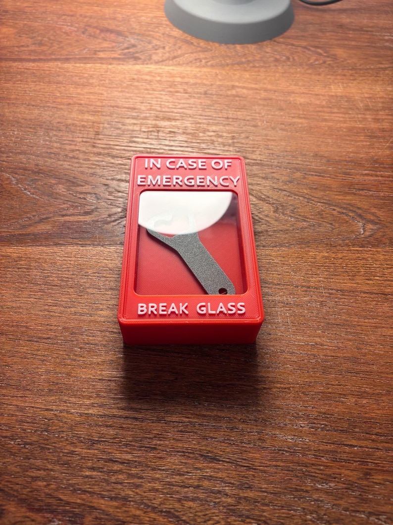 May include: Red break glass box with the text "IN CASE OF EMERGENCY" and "BREAK GLASS" in white lettering. A small metal tool is visible inside the box.