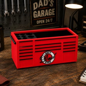 May include: A red toolbox with black accents and the words "BEST DAD EVER" on the front. The toolbox has a black interior and a handle on each side. A black mug with the words "Fueled by Coffee Built by Dad" is on the left.