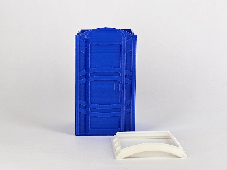 May include: A blue plastic portable toilet model with a white plastic lid. The toilet has a door and a handle.
