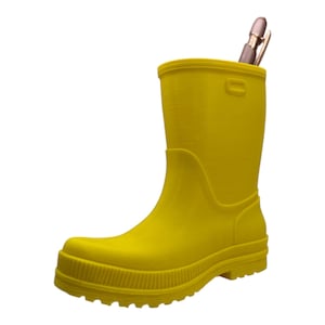 Può includere: Un organizer da scrivania a forma di stivale di gomma giallo brillante. Due penne sono poste all'interno dello stivale. Lo stivale ha una suola scanalata e una finitura liscia e lucida. Un divertente accessorio da scrivania.