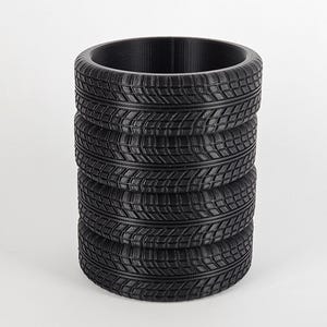 May include: A black, cylindrical pencil holder made from stacked tire tread patterns.