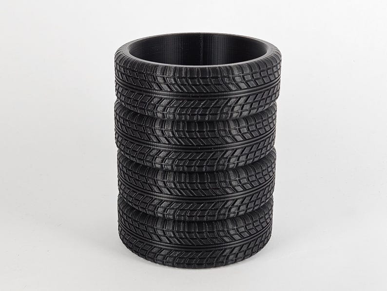 May include: A black, cylindrical pencil holder made from stacked tire tread patterns.