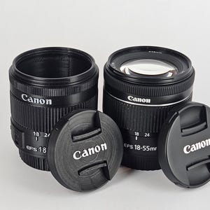 May include: Two black Canon camera lenses with lens caps. The lenses are labeled "Canon EFS 18-55mm" and "Canon EFS 18-24mm".