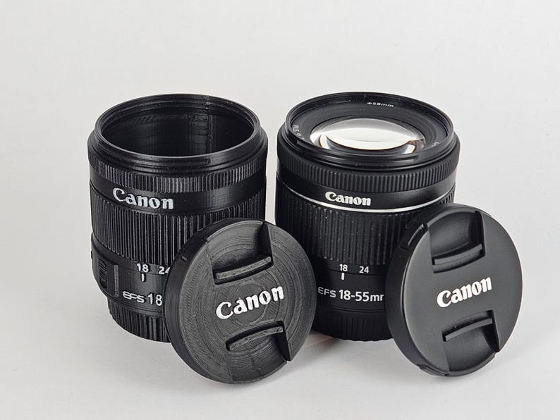 May include: Two black Canon camera lenses with lens caps. The lenses are labeled "Canon EFS 18-55mm" and "Canon EFS 18-24mm".