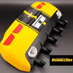 Puede incluir: Un modelo Bumblebee Camaro amarillo y negro con detalles en rojo. El modelo presenta la palabra "Camaro" en un rect&aacute;ngulo blanco y el logotipo de Transformers. El modelo tiene un dise&ntilde;o detallado y est&aacute; sobre un fondo oscuro.