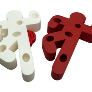 May include: Two doorstop figures shaped like stick figures, one white and one red. Both figures have holes in them.