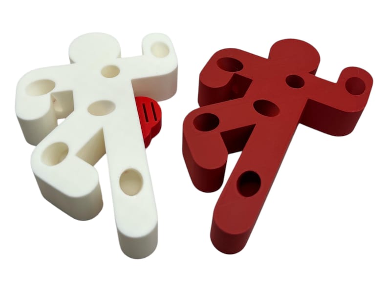 May include: Two doorstop figures shaped like stick figures, one white and one red. Both figures have holes in them.