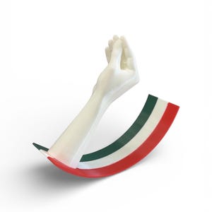 Op de afbeelding: Een witte sculptuur van een hand die het Italiaanse handgebaar maakt, met een gebogen basis in de kleuren van de Italiaanse vlag: rood, wit en groen. De sculptuur staat tegen een witte achtergrond.