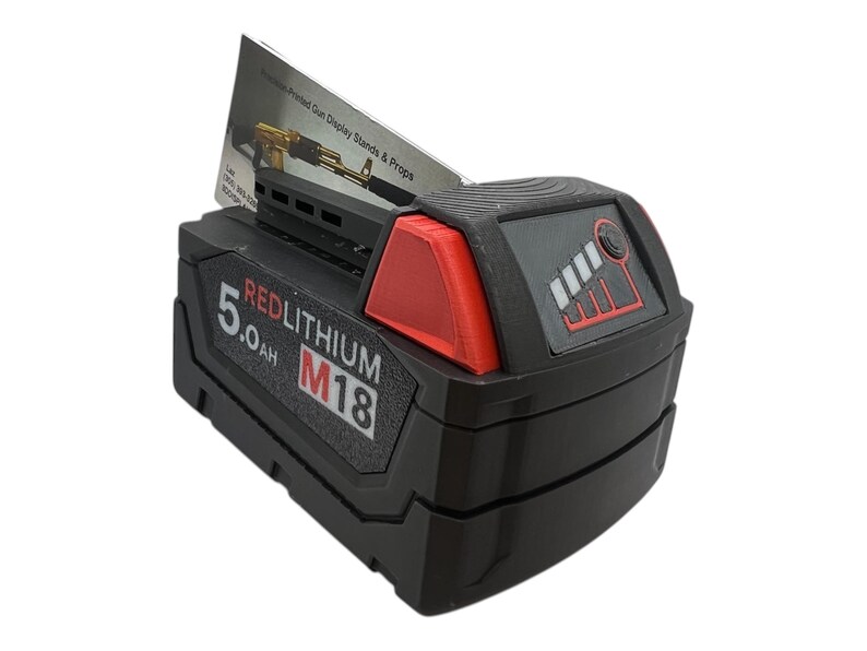 May include: A black and red Milwaukee REDLITHIUM M18 battery with a 5.0 Ah capacity. The battery has a fuel gauge with five bars and a red indicator light.