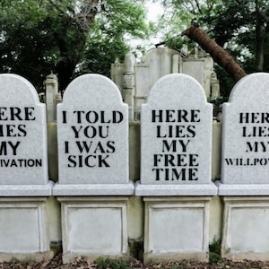May include: Four gray tombstones with humorous epitaphs. The inscriptions read: "Here Lies My Motivation," "I Told You I Was Sick," "Here Lies My Free Time," and "Here Lies My Willpower."