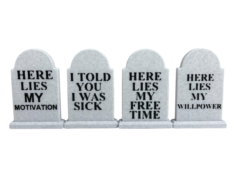 May include: Four gray tombstone decorations with black text. The tombstones read: "HERE LIES MY MOTIVATION", "I TOLD YOU I WAS SICK", "HERE LIES MY FREE TIME", and "HERE LIES MY WILLPOWER".