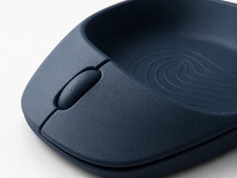 Op de afbeelding: Close-up van een marineblauwe ergonomische computermuis. De muis heeft een getextureerd oppervlak en een scrollwiel. Het ontwerp omvat een gebogen inkeping voor de hand en een golfachtig patroon.