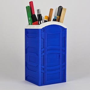 May include: A blue and white plastic portable toilet shaped desk organizer with a white top and a blue body. The organizer is filled with pens, pencils, and markers.