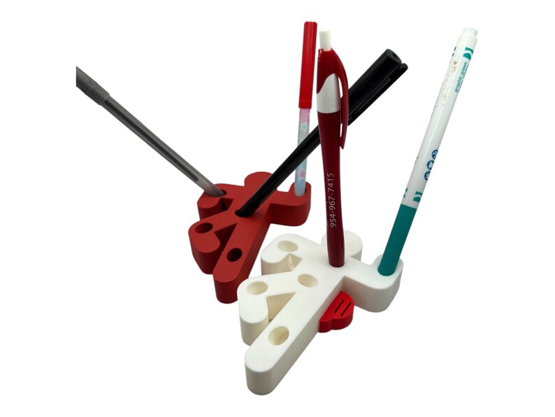 May include: A white and red desk organizer shaped like a person holding a pen. The organizer has multiple slots for pens, pencils, and other office supplies.