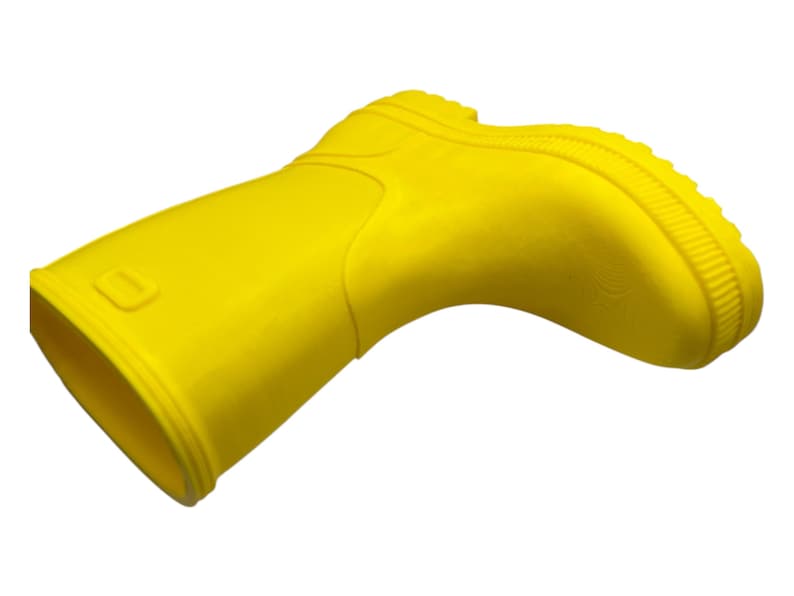 May include: A bright yellow rubber boot, angled slightly to the right, against a white background. The boot has a rounded toe, a textured sole, and a small rectangular detail near the top. The boot is likely for children.