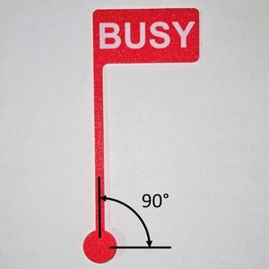 May include: A red flag-shaped sign with the word "BUSY" in white capital letters. The sign has a long, thin stem ending in a red circle. A 90-degree angle is indicated with a curved arrow.