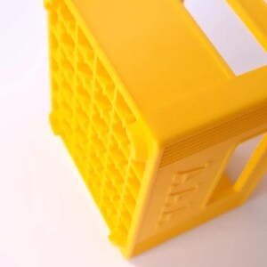 May include: A bright yellow plastic crate, featuring a grid pattern on one side. The crate is rectangular with a handle on top. The side of the crate has the letters "AAA" embossed on it.