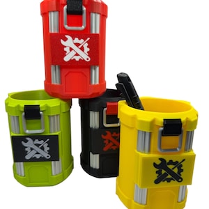 May include: Four cylindrical containers in red, lime green, black, and yellow, each featuring vertical silver-toned accents, a black latch, and a rectangular patch displaying a white or black gear and wrench icon. One black pen rests inside the yellow cup.