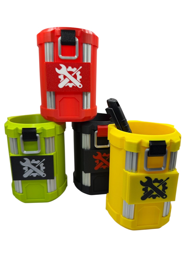 May include: Four cylindrical containers in red, lime green, black, and yellow, each featuring vertical silver-toned accents, a black latch, and a rectangular patch displaying a white or black gear and wrench icon. One black pen rests inside the yellow cup.