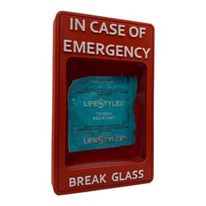 May include: A red plastic box with the words "IN CASE OF EMERGENCY" and "BREAK GLASS" in white lettering. Inside the box is a blue and white Lifestyles condom packet.