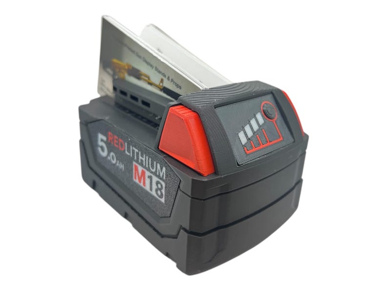 May include: A black and red power tool battery with the text "REDLITHIUM M18 5.0 Ah" on the side. The battery has a fuel gauge with five bars, four of which are lit up.