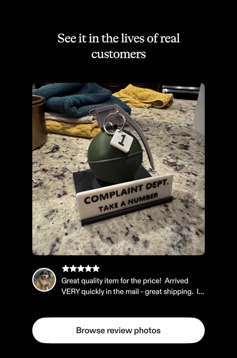 May include: A novelty item featuring a green grenade with a metal pull ring and a small tag with the number 1. Below it is a sign that reads "COMPLAINT DEPT. TAKE A NUMBER."