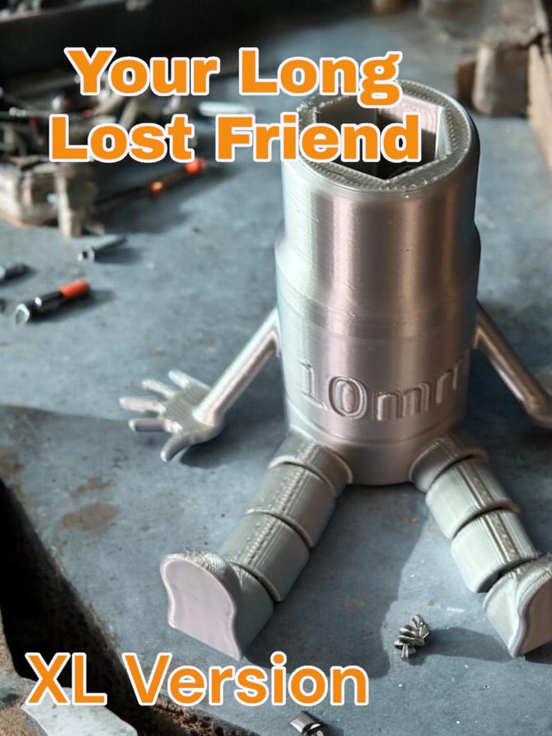 May include: A silver 3D printed model of a 10mm socket wrench with legs and arms. The model is sitting on a textured surface. The text "Your Long Lost Friend" and "XL Version" are visible in the image.