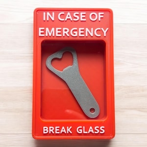 May include: Red break glass box with the text "IN CASE OF EMERGENCY" and "BREAK GLASS" in white lettering. A silver bottle opener is inside the box.